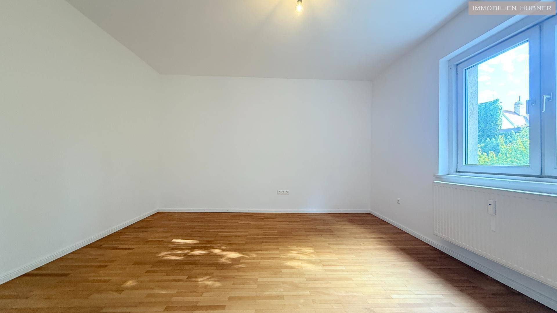 Geräumiges Schlafzimmer mit Parkettboden und großem Fenster.
