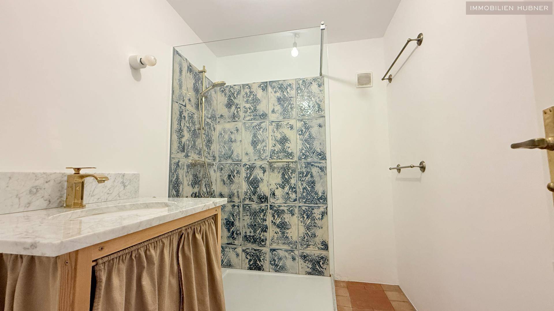 Modernes Badezimmer mit Dusche, Marmorwaschtisch und dekorativen Fliesen.