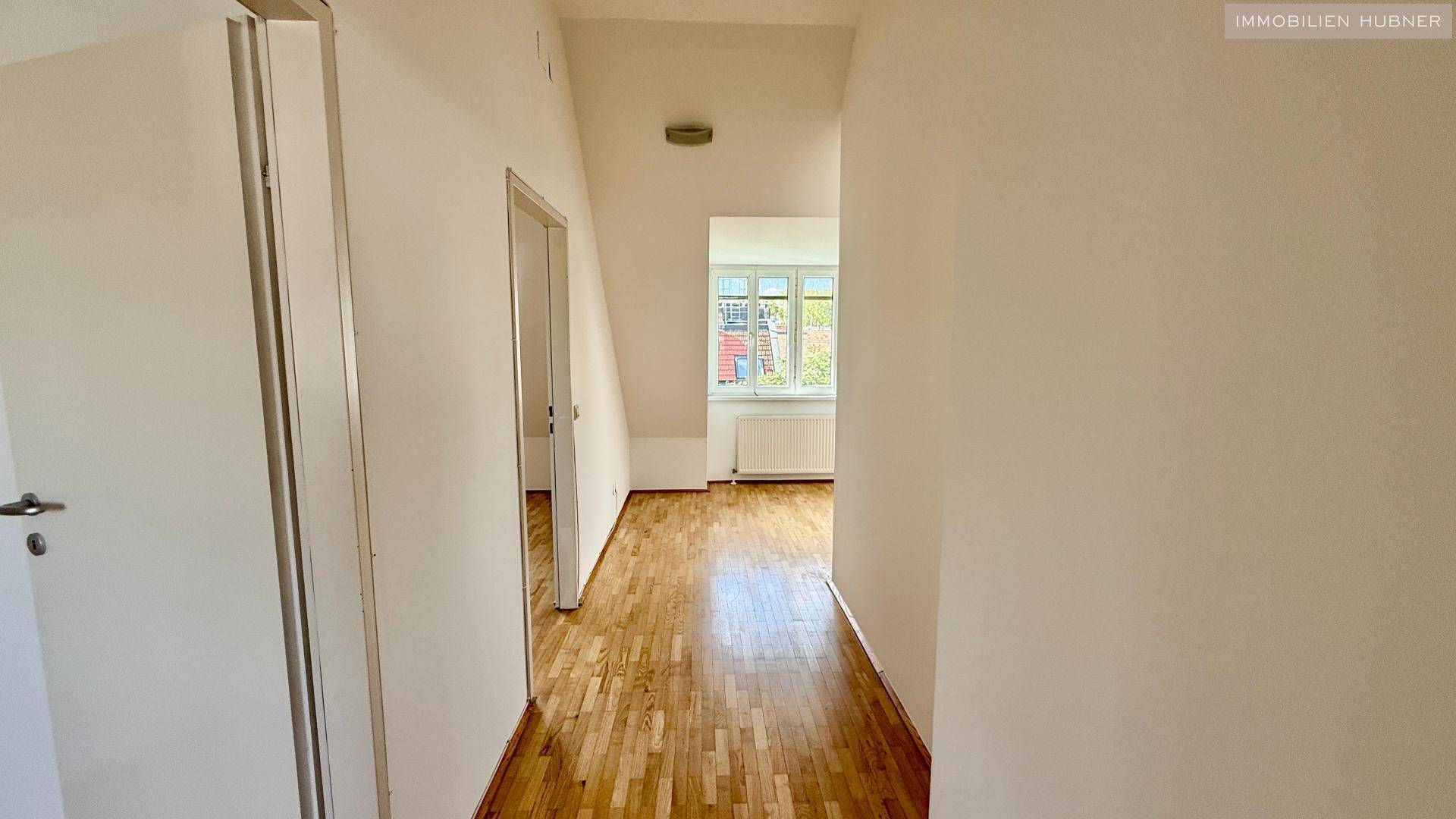 Flur im Dachgeschoss mit Holzboden und Zugang zu weiteren Zimmern, hell und funktional.