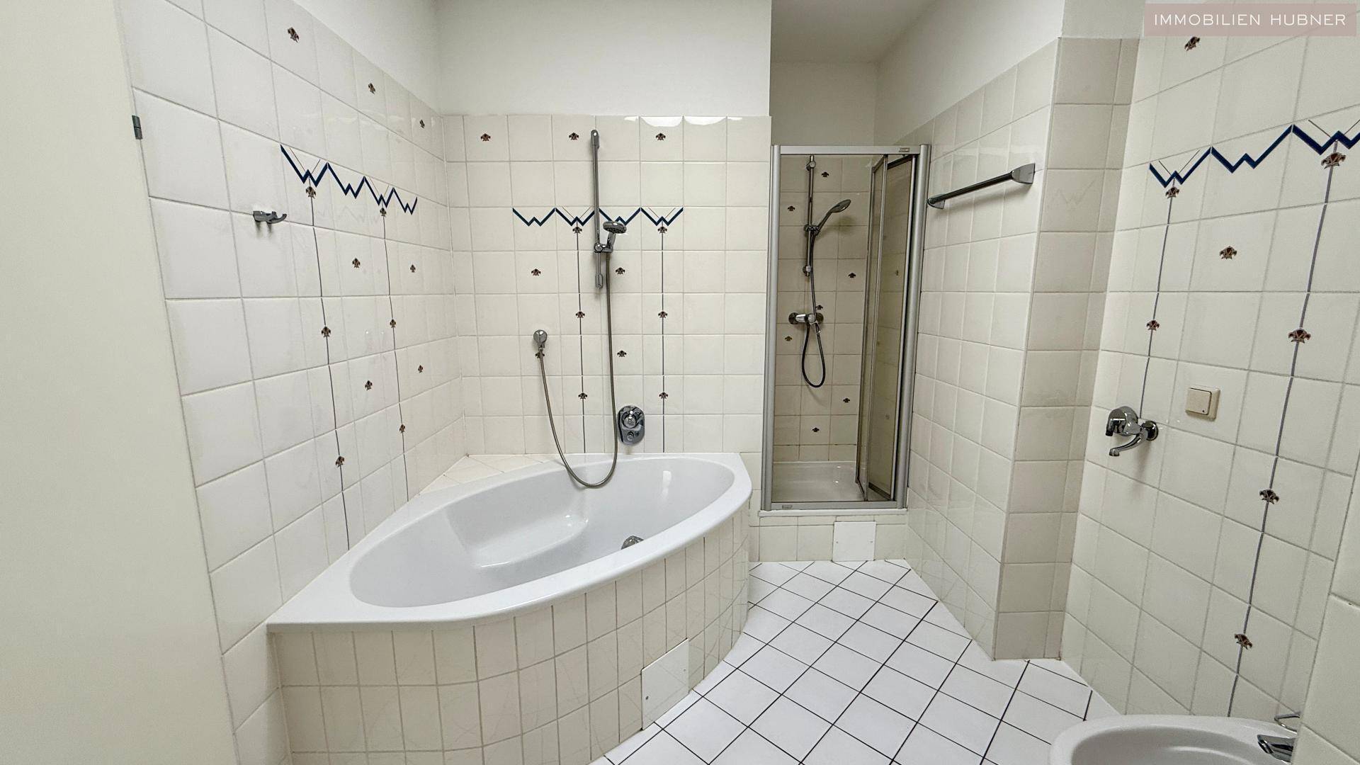 Badezimmer mit Eckbadewanne, Duschkabine und weißen Fliesen, funktional eingerichtet.