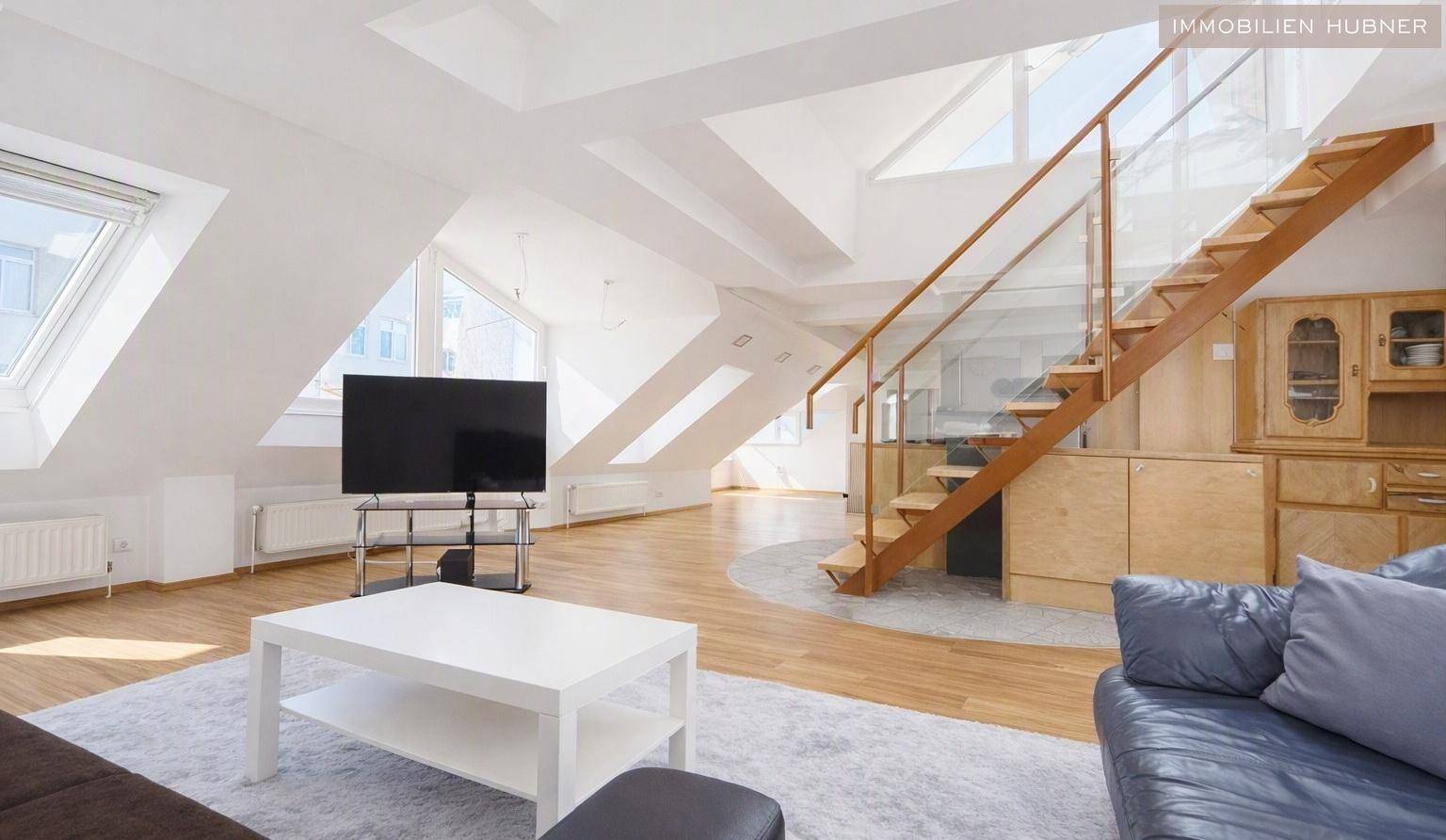 Heller Wohnbereich mit moderner Treppe, Dachschrägen und Oberlichtern, die den Raum mit Tageslicht füllen.