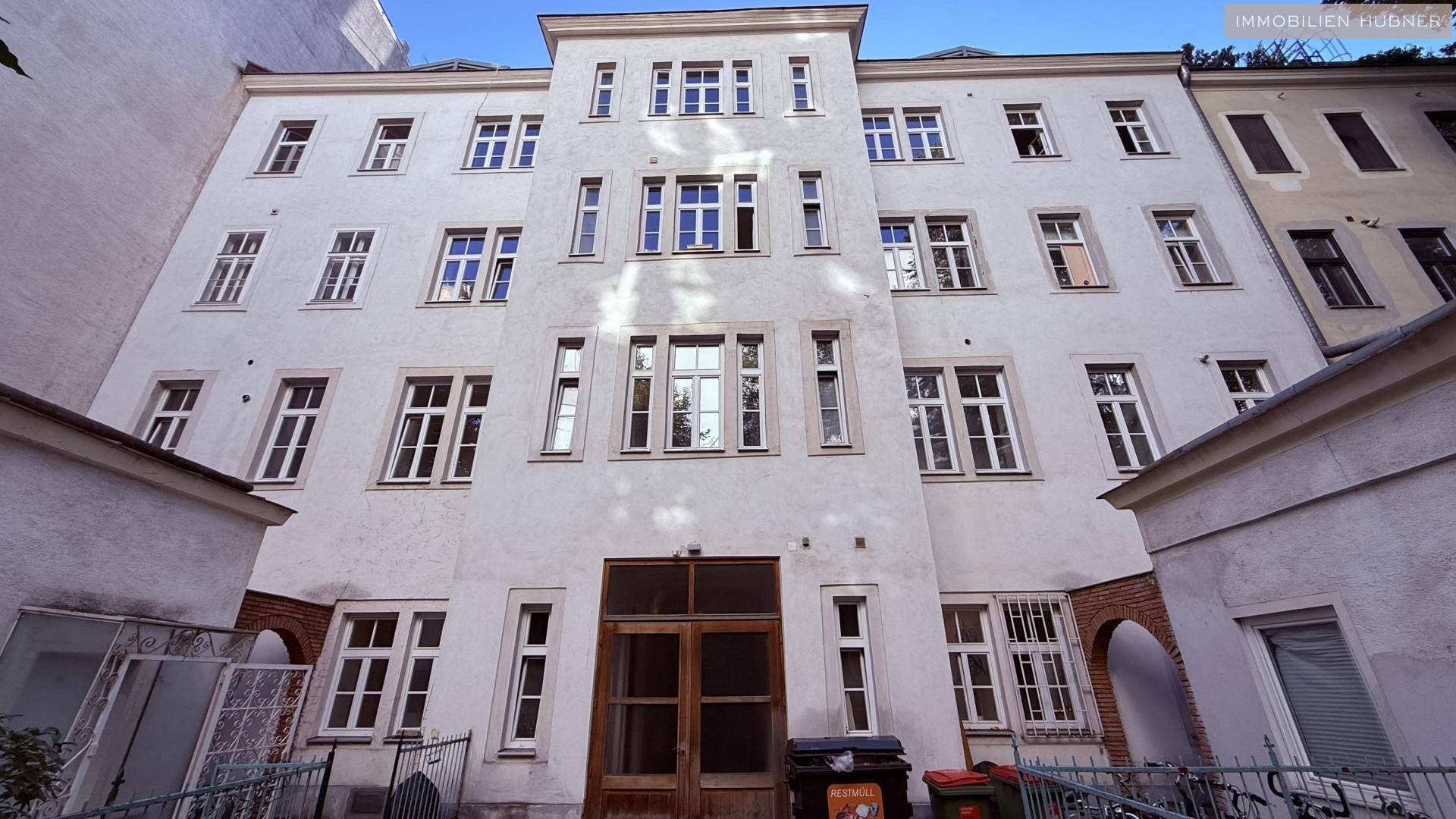 Klassische Gebäudefassade mit vielen Fenstern und einem Eingangsbereich, typisch für einen Innenhof.