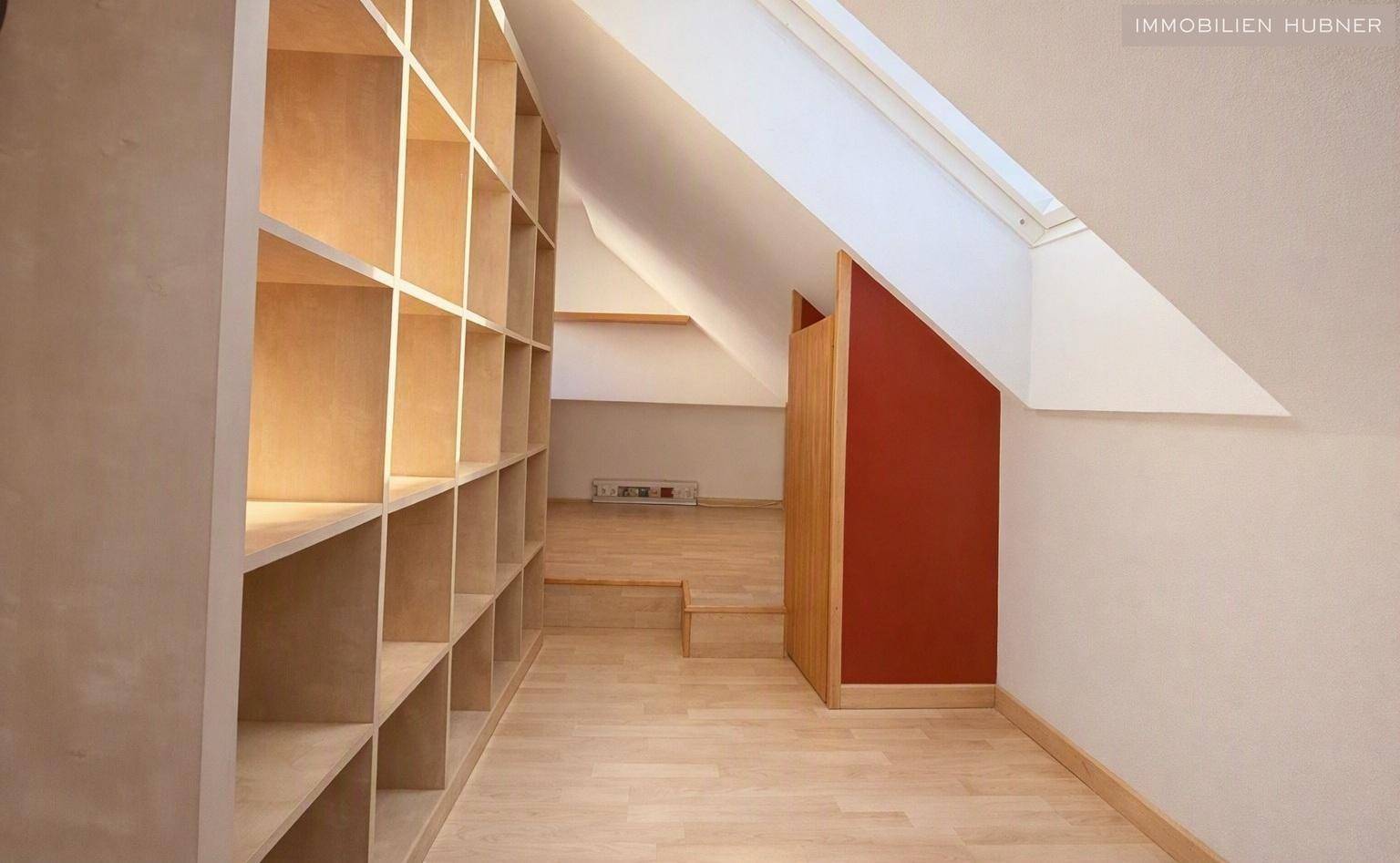 Raum mit integrierten Holzregalen, Holzboden und einem Dachfenster, ideal als Stauraum oder Arbeitsbereich.