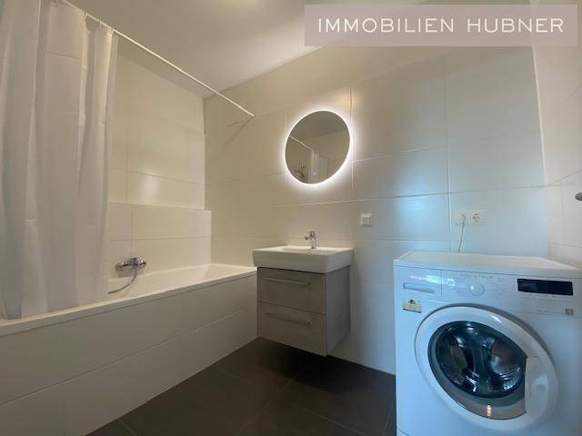 Modernes Badezimmer mit Badewanne, Waschbecken und Waschmaschine.