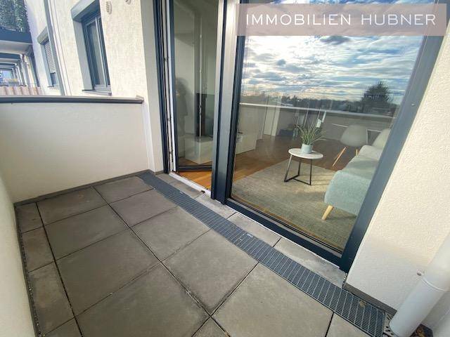 Kleiner Balkon mit Fliesenboden und Blick in den Wohnbereich.