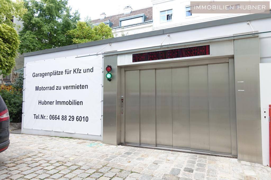 Eingang zur Tiefgarage mit Metalltür, Verkehrsampel und Werbeschild für Stellplätze.