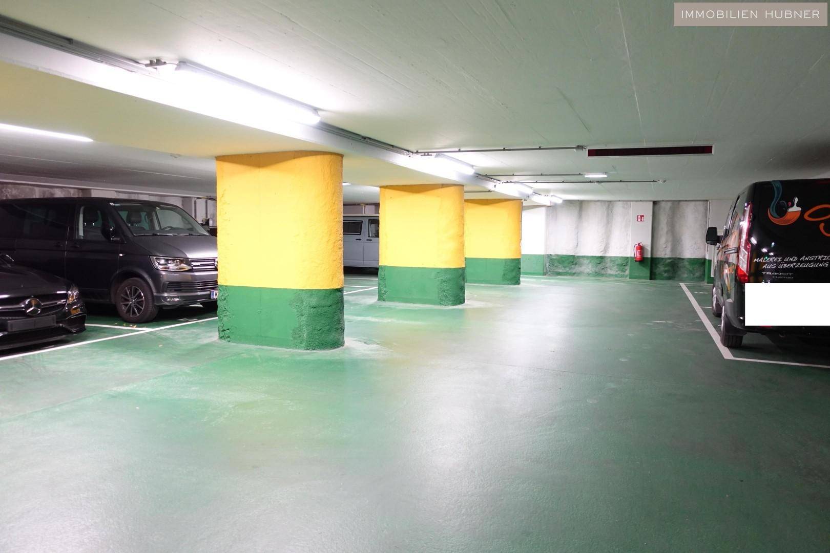 Geräumige Tiefgarage mit mehreren Stellplätzen, gelben Säulen und grüner Bodenmarkierung.