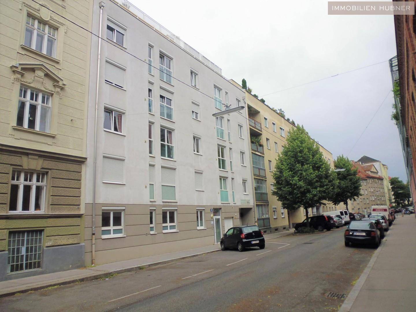 Straßenansicht eines mehrstöckigen Wohngebäudes mit vielen Fenstern und Balkonen.