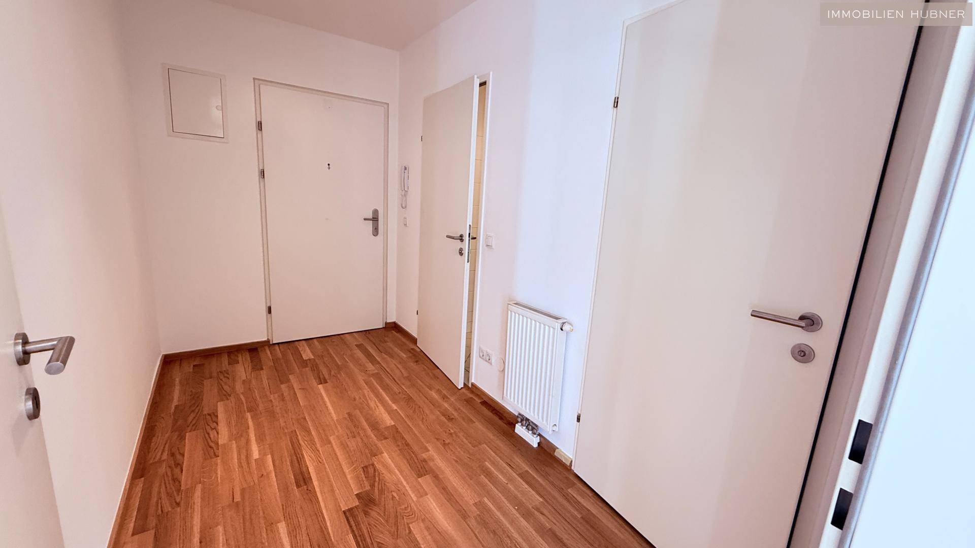 Heller Flur mit Holzparkettboden und mehreren Türen, der den Eingangsbereich erschließt.