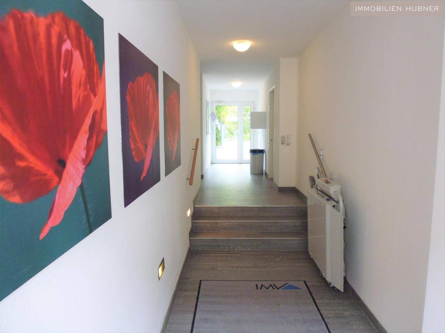 Heller Flur mit Treppe und einem Treppenlift für barrierefreien Zugang zu den oberen Etagen.