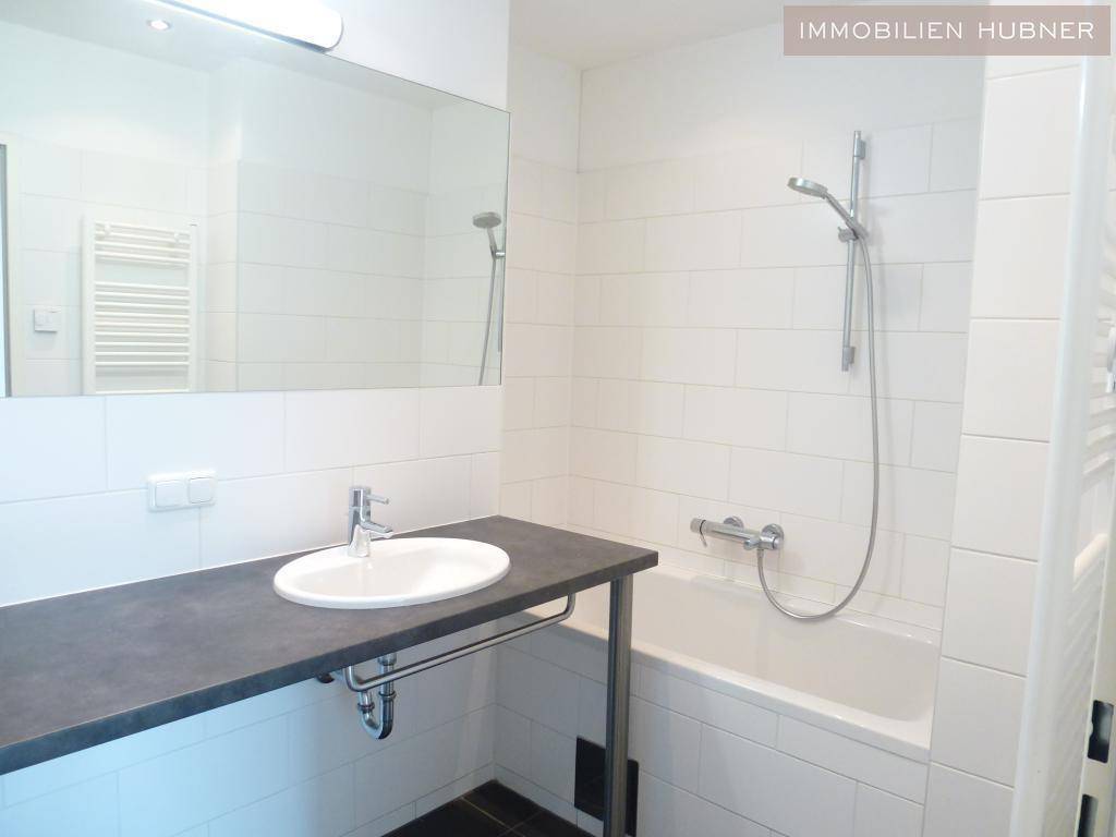 Modernes Badezimmer mit Badewanne, Duschvorrichtung, Waschbecken und großem Spiegel.