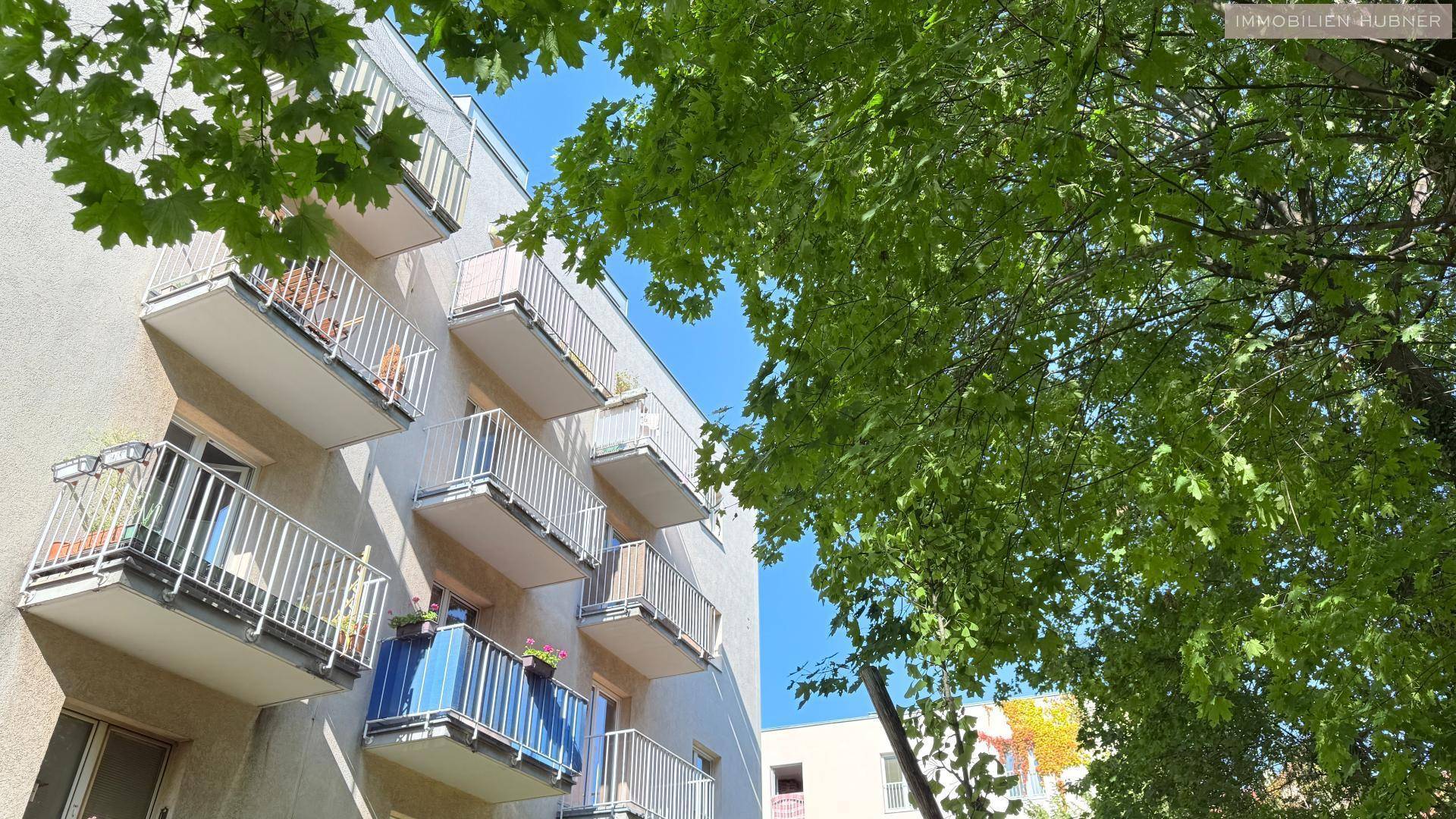 Mehrere Balkone an der Fassade eines Wohngebäudes, umgeben von üppigem Grün.