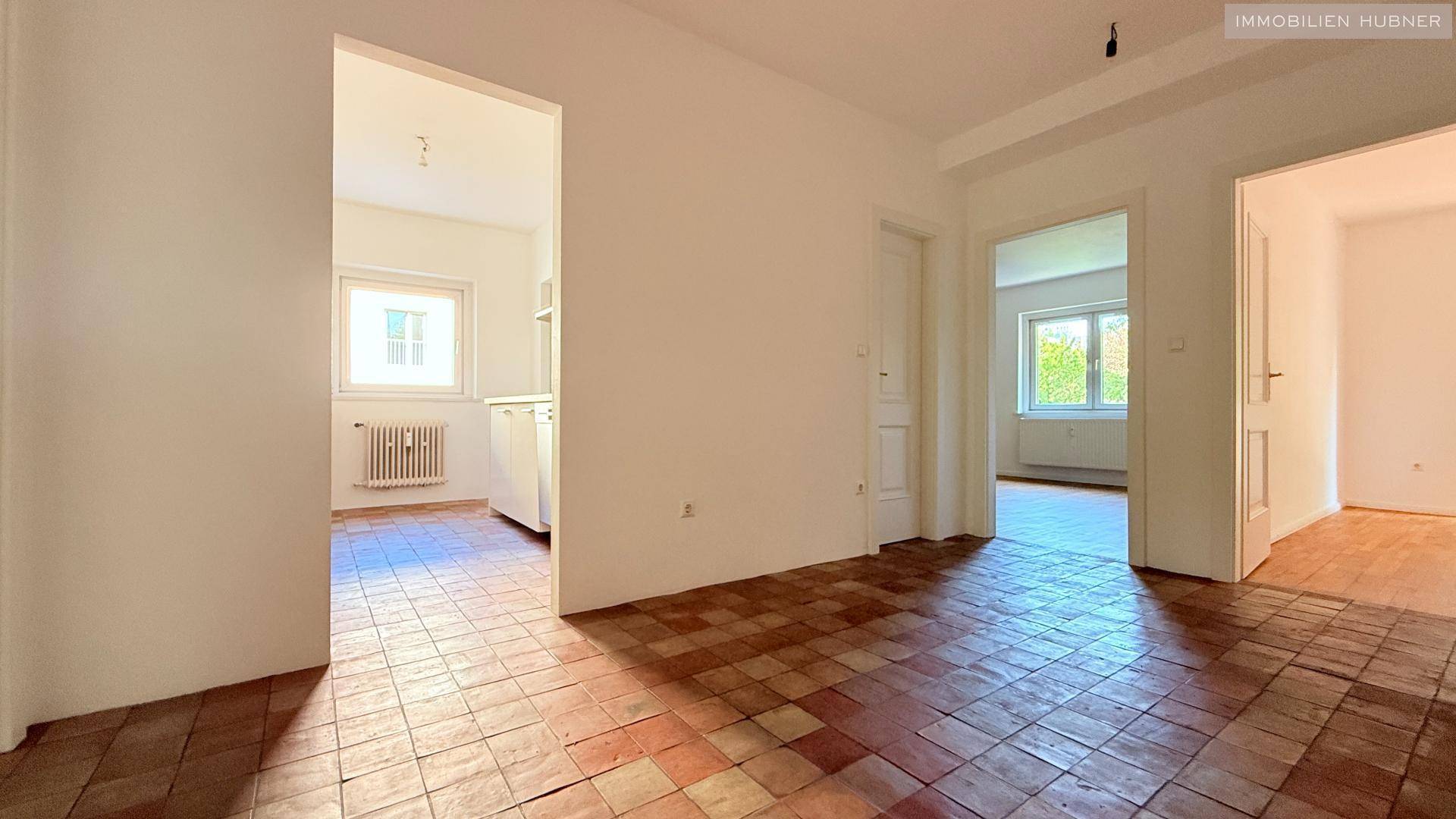 Geräumiger Flur mit Terrakotta-Fliesenboden und Blick in die Küche und weitere Räume.