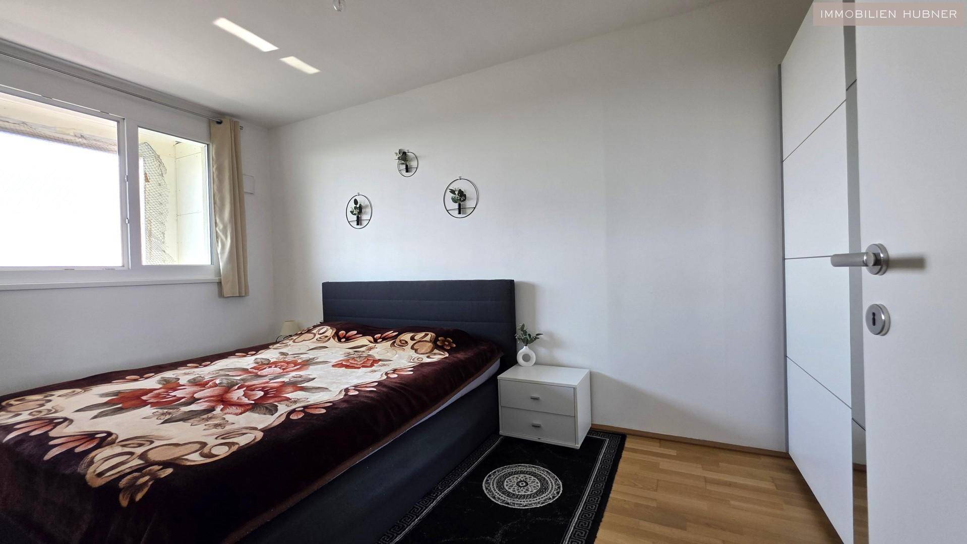 Schlafzimmer mit Doppelbett, Nachttisch und Holzfußboden.