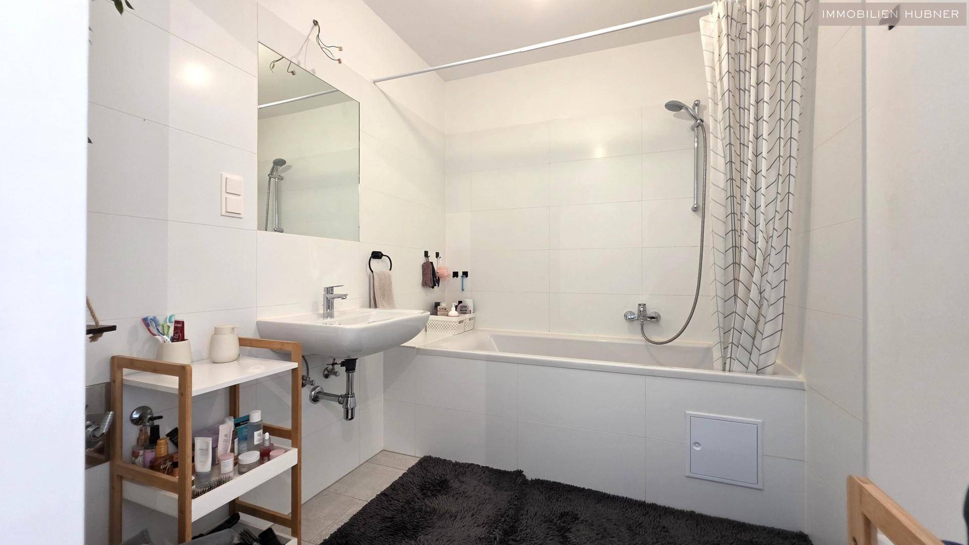 Modernes Badezimmer mit Badewanne, Dusche und weißen Fliesen.