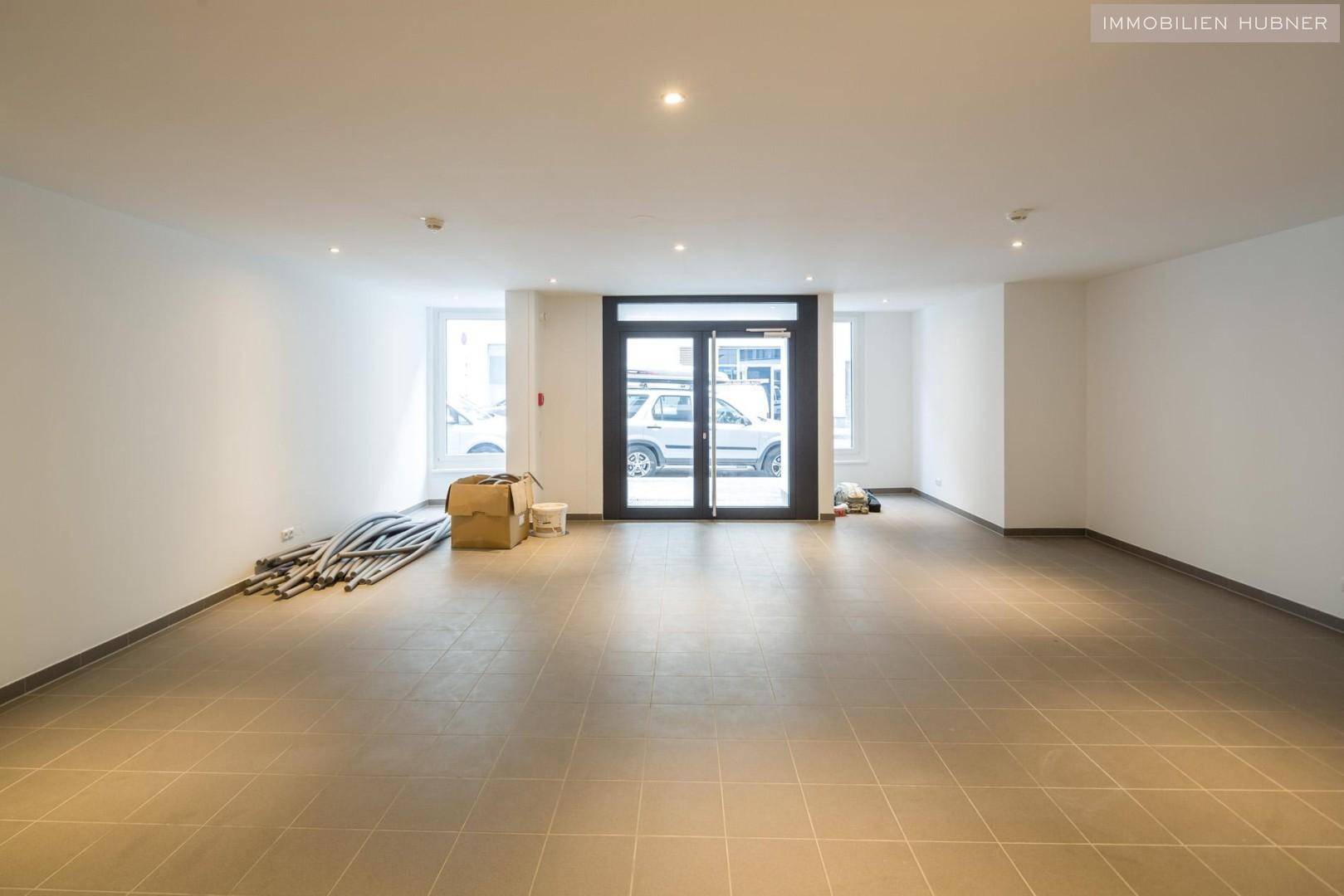 Großer, leerer Geschäftsraum mit Eingangstür und Blick auf die Straße, ideal für verschiedene Nutzungen.