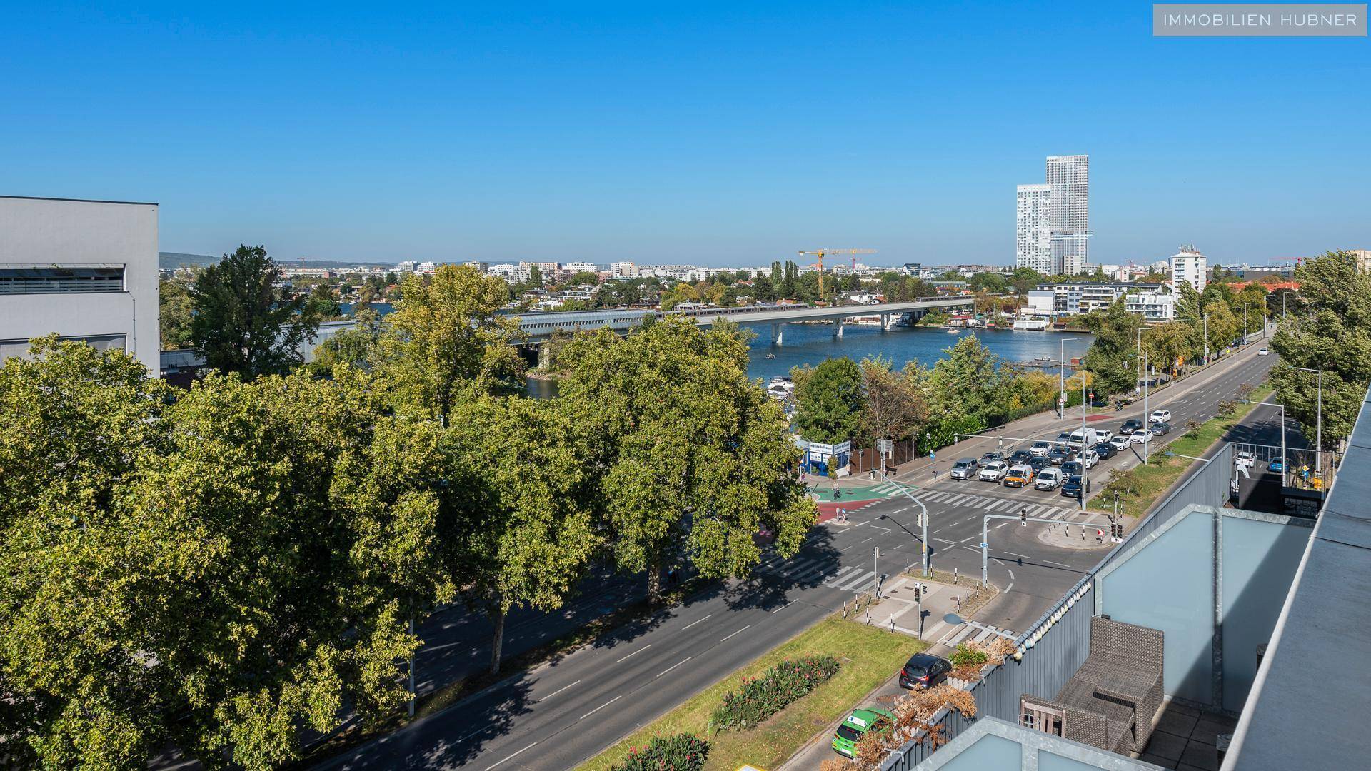 Weitläufiger Blick auf die Stadt, eine Brücke und den Fluss unter klarem Himmel.