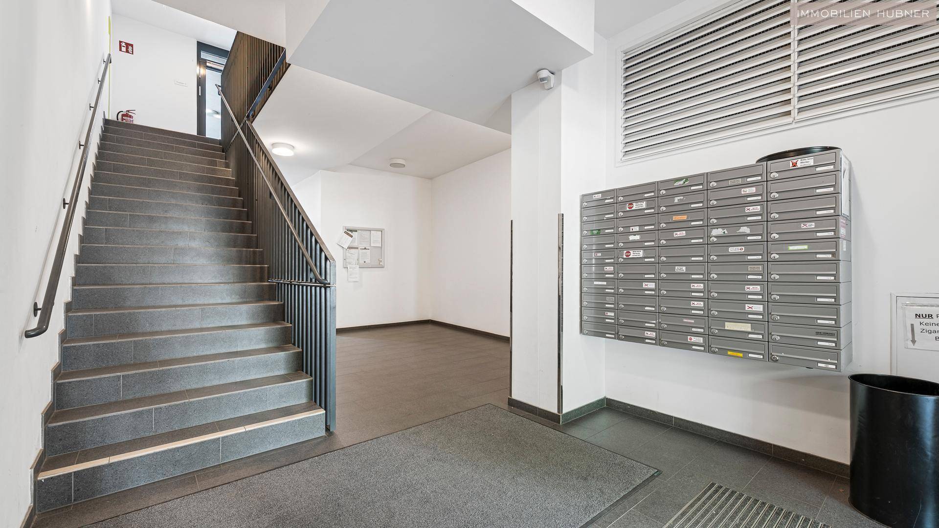 Heller Eingangsbereich mit Treppenhaus und Briefkästen in einem Mehrfamilienhaus.
