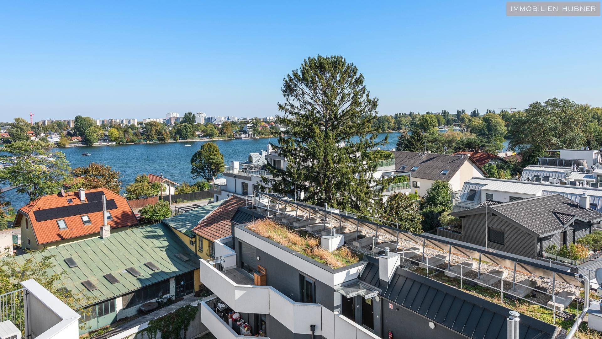 Panoramablick über den See und die umliegenden Häuser mit viel Grün.