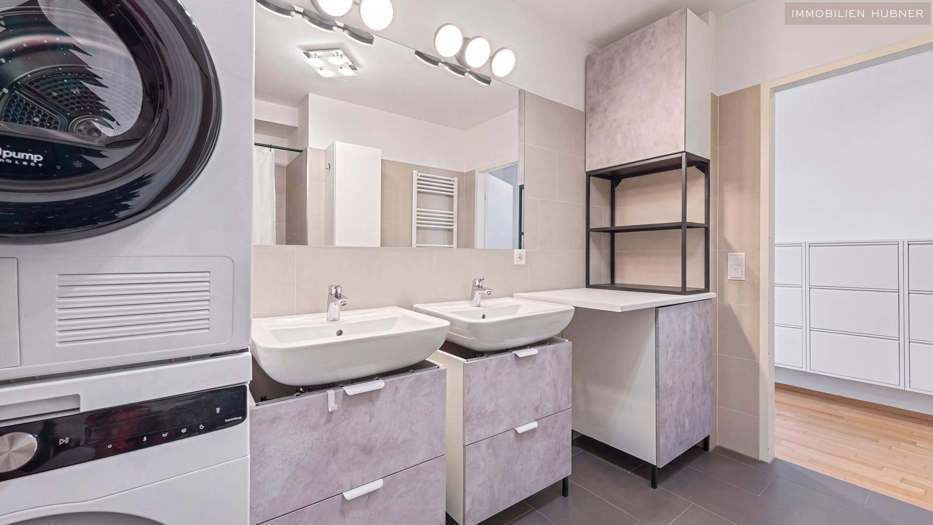 Modernes Badezimmer mit Doppelwaschbecken, Waschmaschine und Trockner.