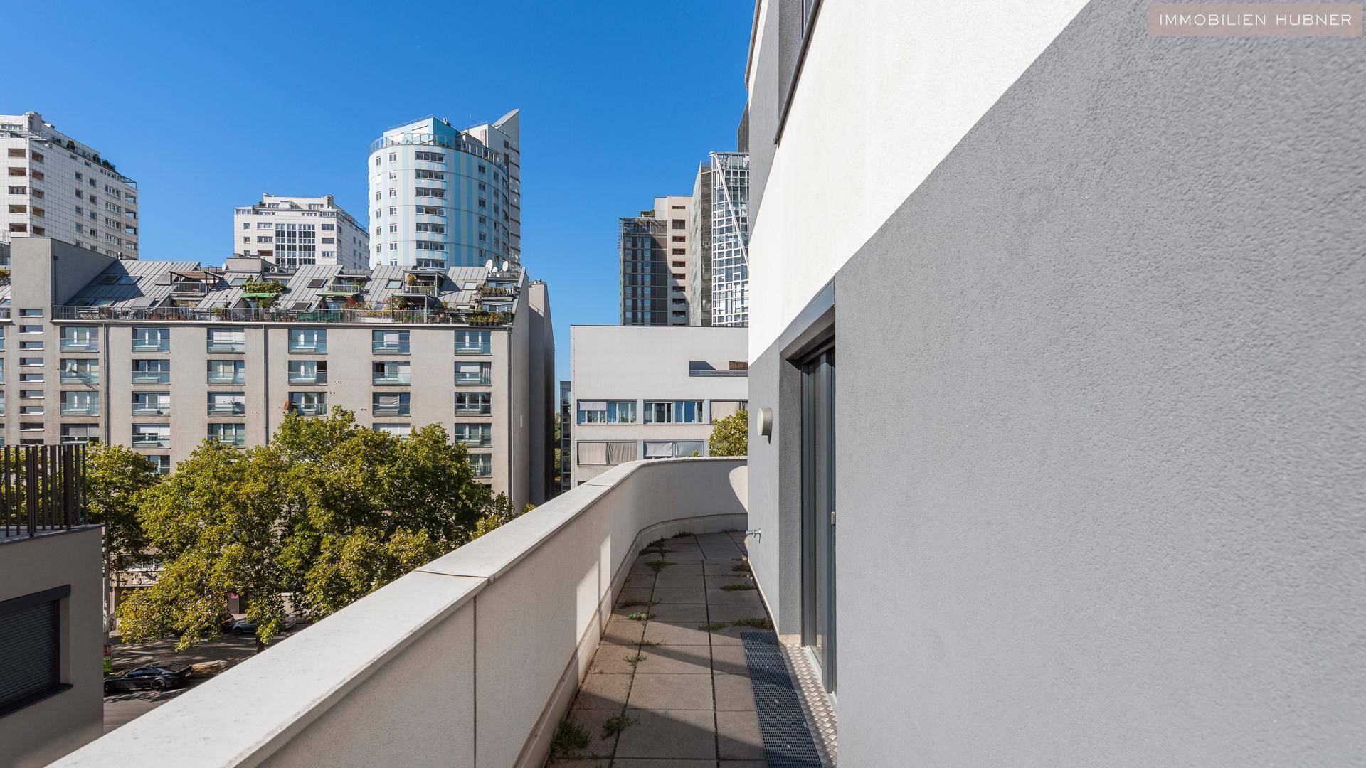 Geschwungener Balkon mit Blick auf die Stadt und moderne Hochhäuser.