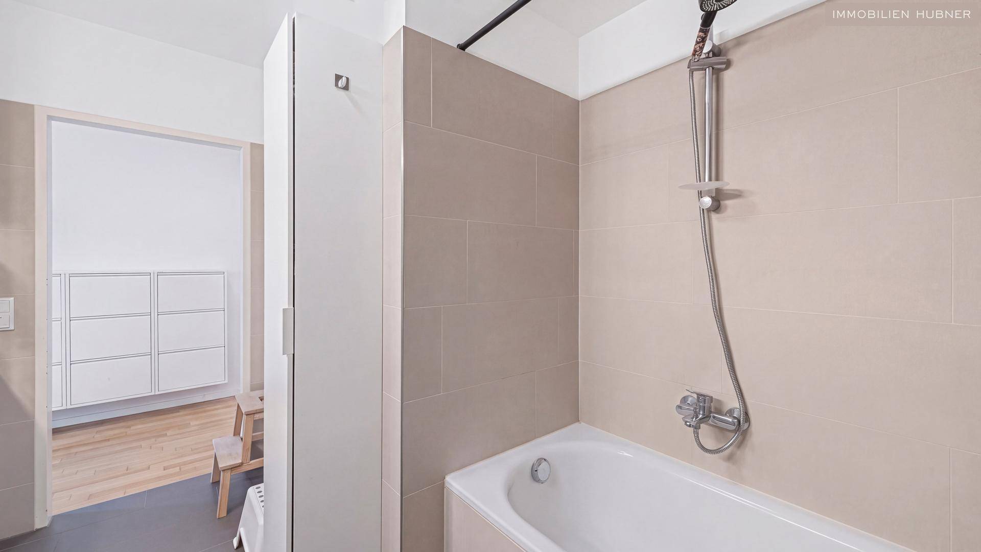 Helles Badezimmer mit Badewanne und Duschfunktion, modern gefliest.