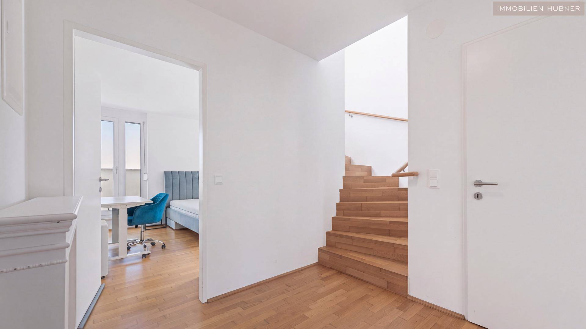 Heller Flur mit Holztreppe, die in die obere Etage führt, und Holzboden.