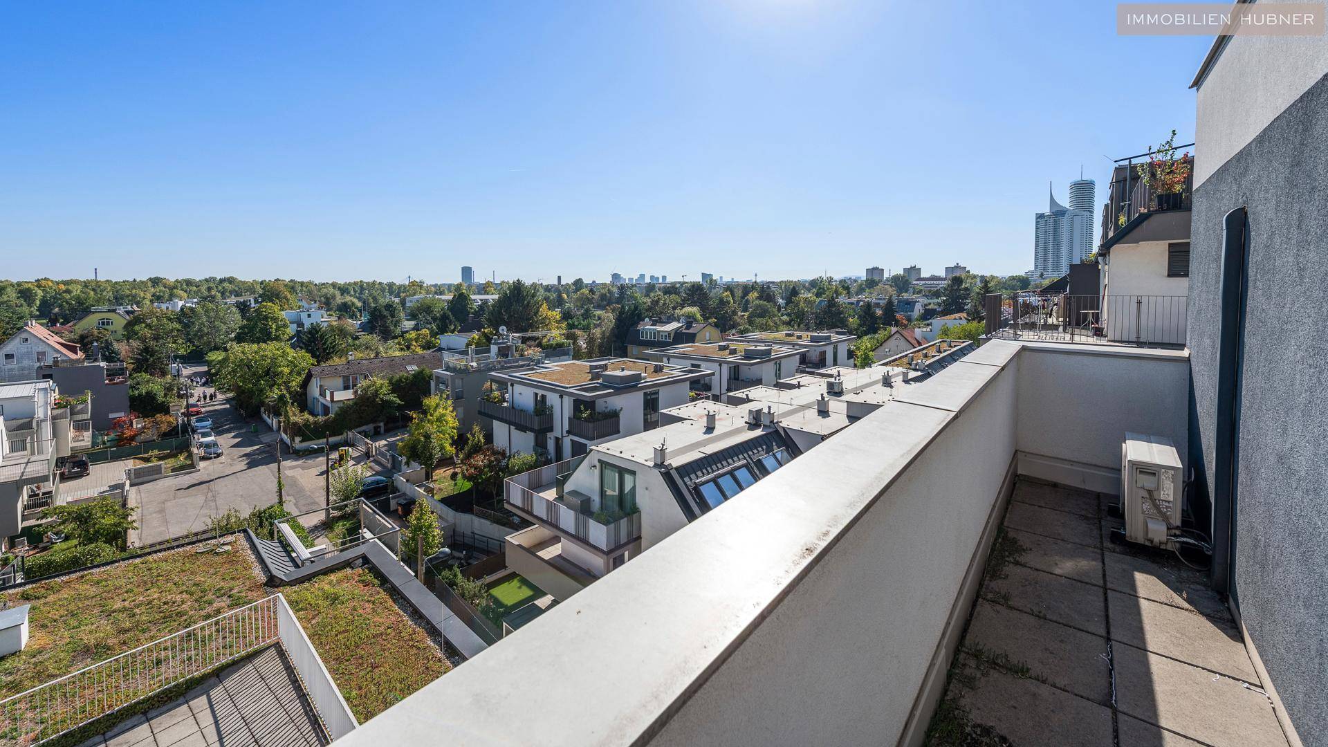 Langer Balkon mit Blick auf die umliegenden Gebäude und viel Grün.