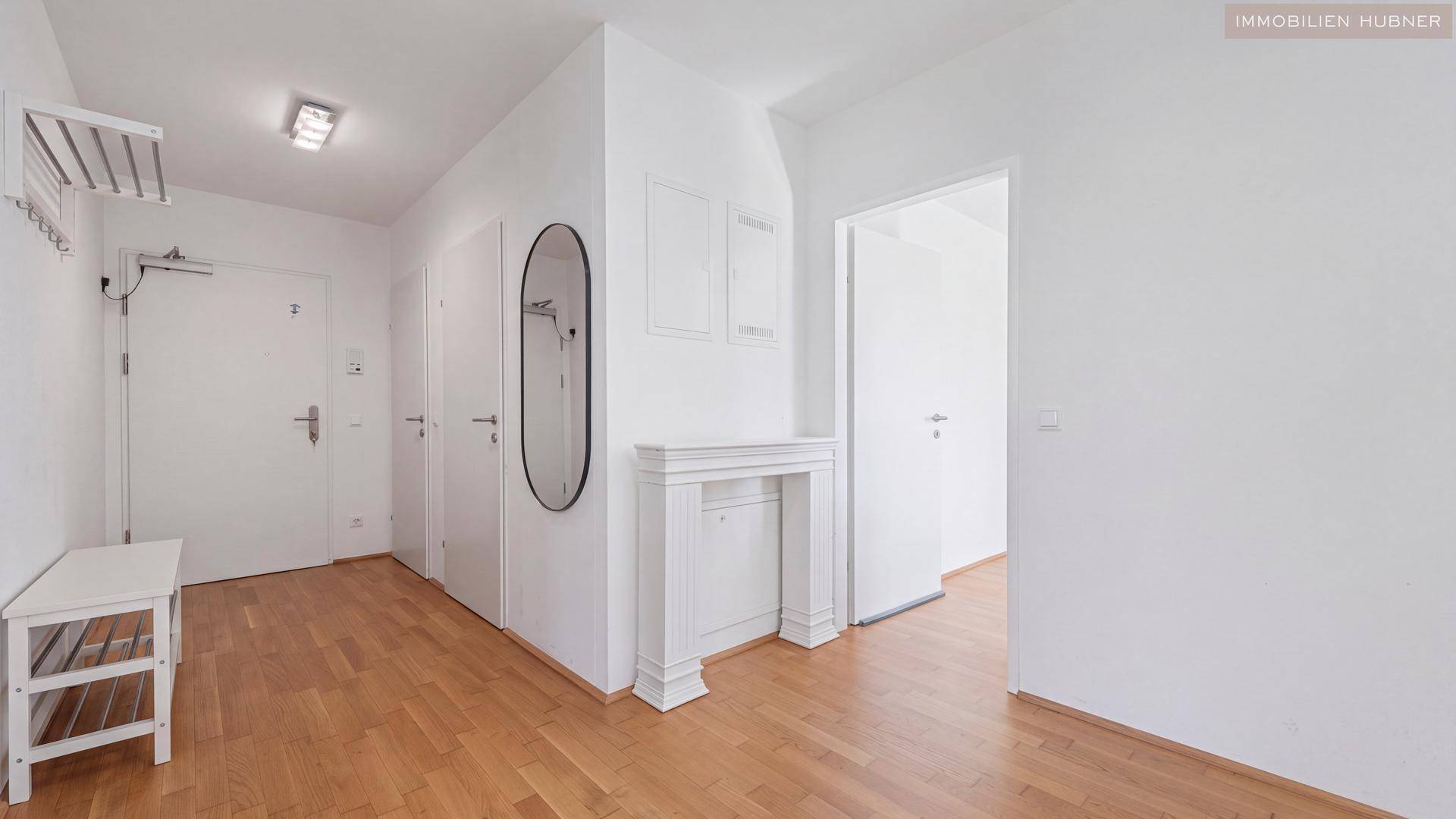 Geräumiger Eingangsbereich mit Holzboden, Garderobe und dekorativem Kamin.