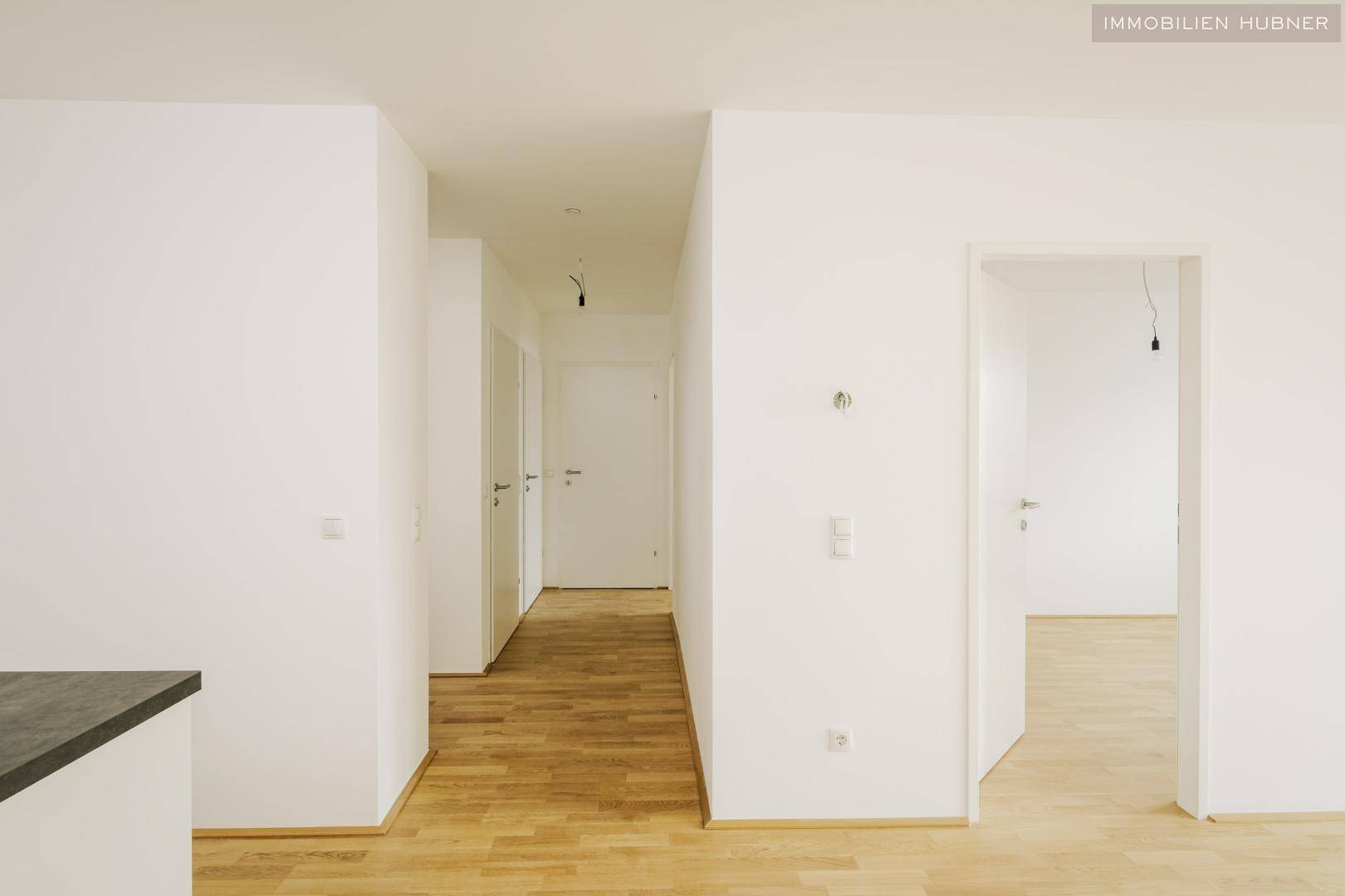 Heller Flur mit Holzboden und Zugang zu verschiedenen Zimmern der Wohnung.