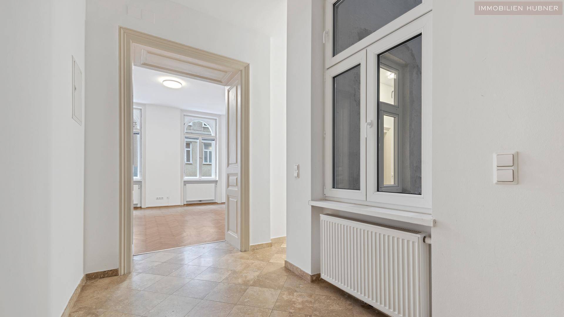 Heller Flur mit Fliesenboden und Blick in ein weiteres Zimmer, typisch für Altbauwohnungen.