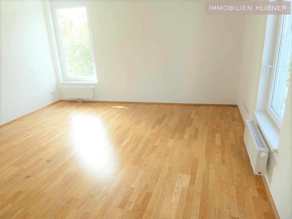 Helles Schlafzimmer mit Parkettboden und zwei Fenstern, die den Raum gut belichten.