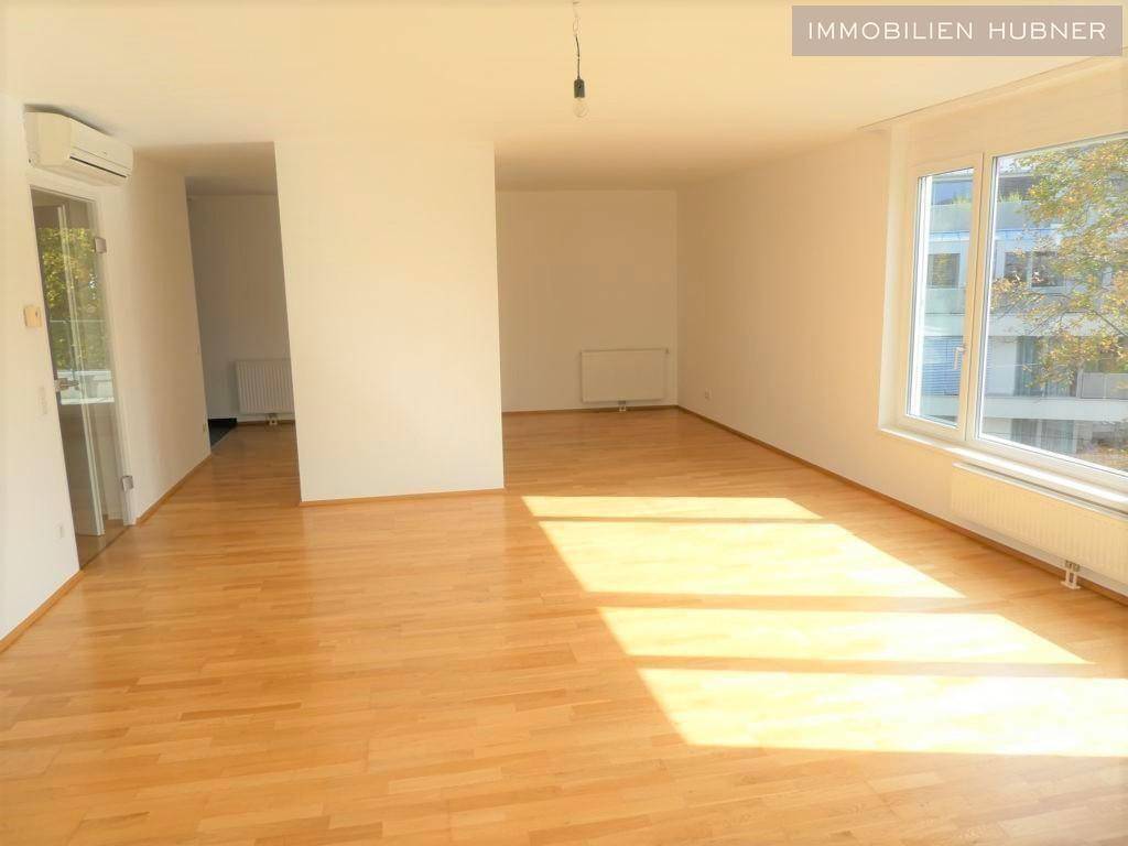 Geräumiges Wohnzimmer mit Parkettboden, großen Fenstern und viel natürlichem Licht.
