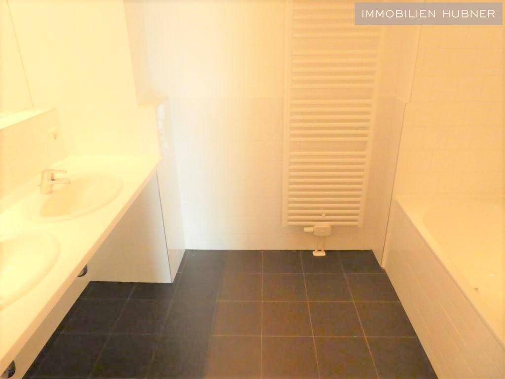 Modernes Badezimmer mit Doppelwaschbecken, Badewanne und beheiztem Handtuchhalter.