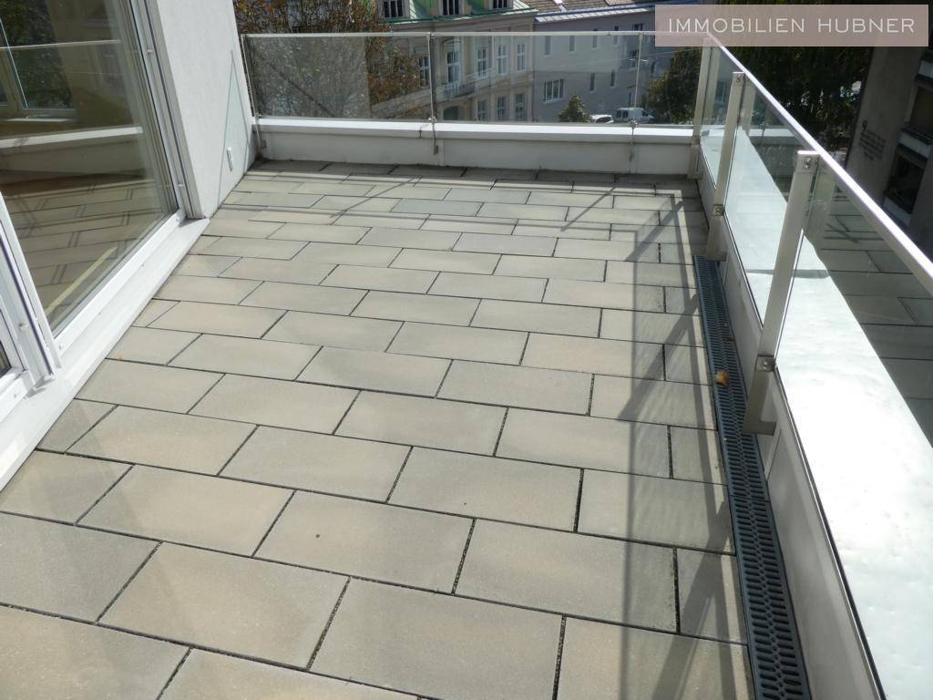 Sonniger Terrassenbereich mit Fliesenboden und Glasgeländer, ideal für Entspannung im Freien.