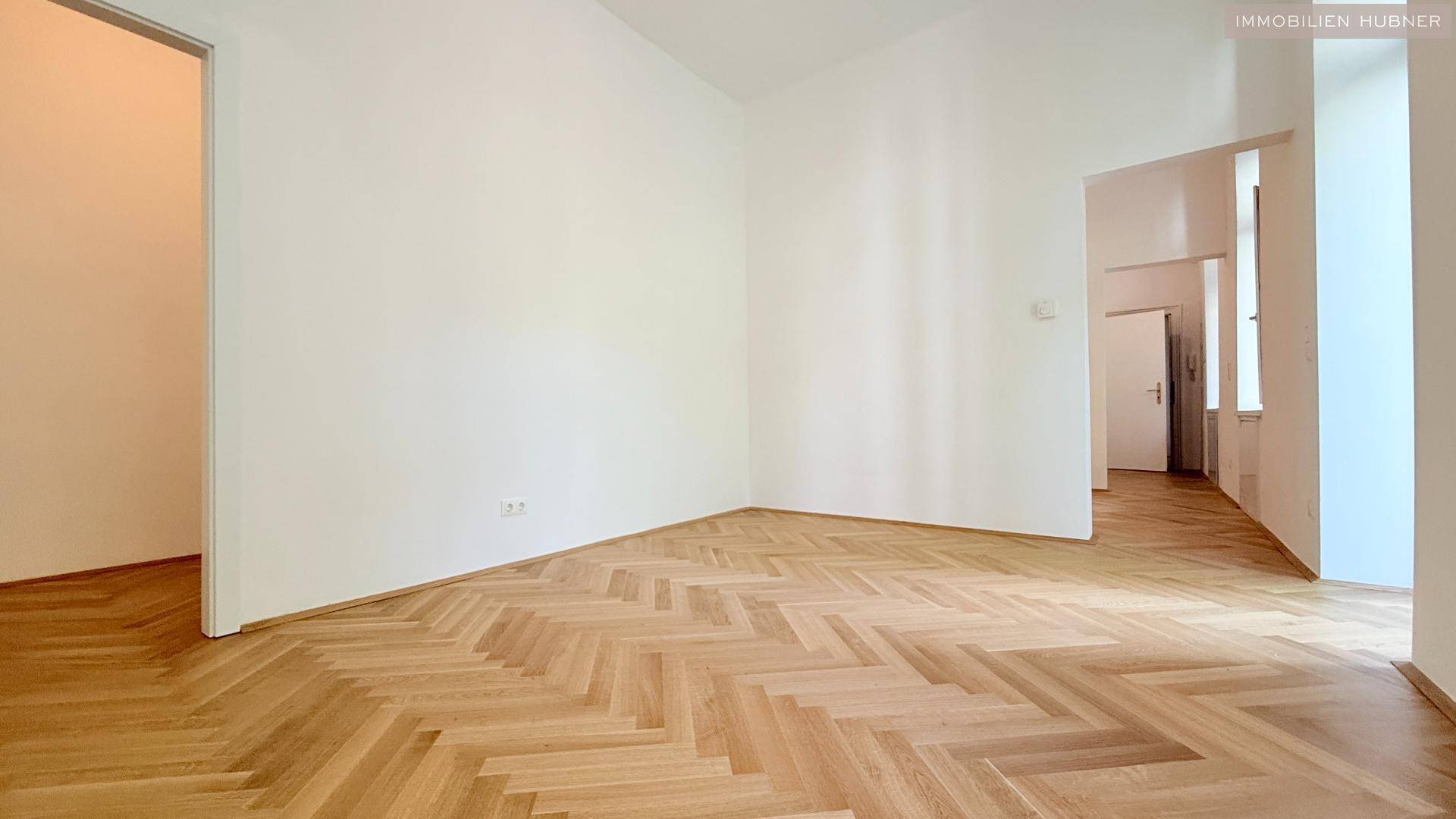 Geräumiger, heller Raum mit Fischgrätparkett und weiß gestrichenen Wänden, bereit zur Gestaltung.