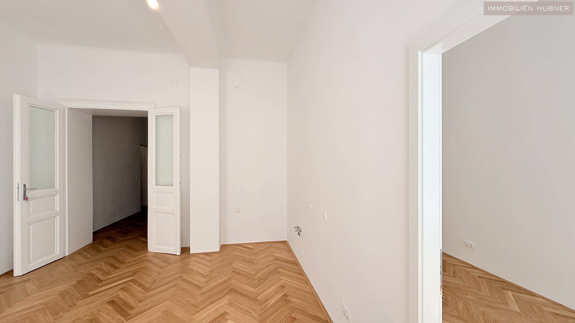 Geräumiges Zimmer mit Fischgrätparkett und hohen Türen, das viel Potenzial zur Gestaltung bietet.
