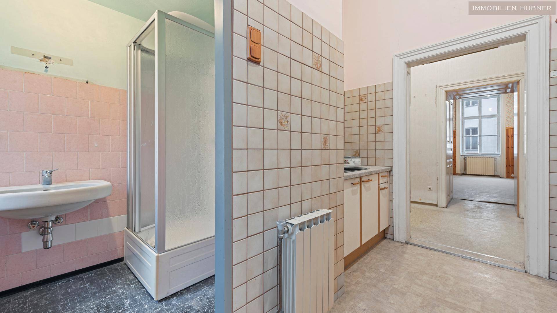Badezimmer mit Duschkabine, Waschbecken und Fliesen, das eine Modernisierung benötigt.