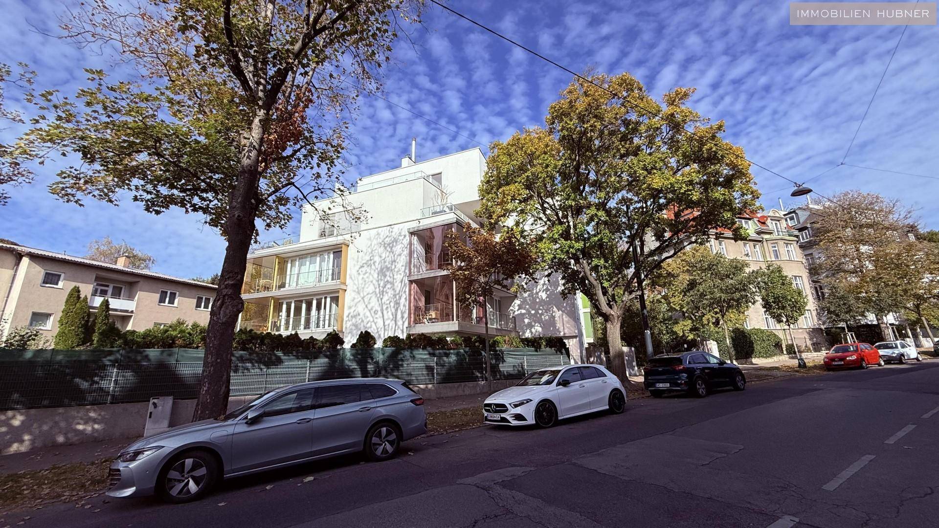 Moderne Wohnanlage mit mehreren Etagen und großen Fenstern, an einer städtischen Straße gelegen.