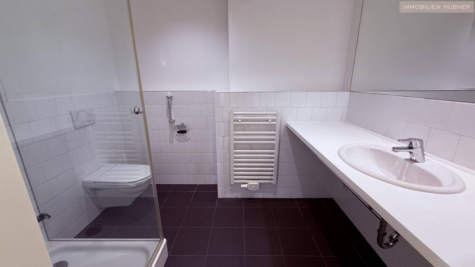 Funktionales Badezimmer mit ebenerdiger Dusche, Einzelwaschbecken und beheiztem Handtuchhalter.
