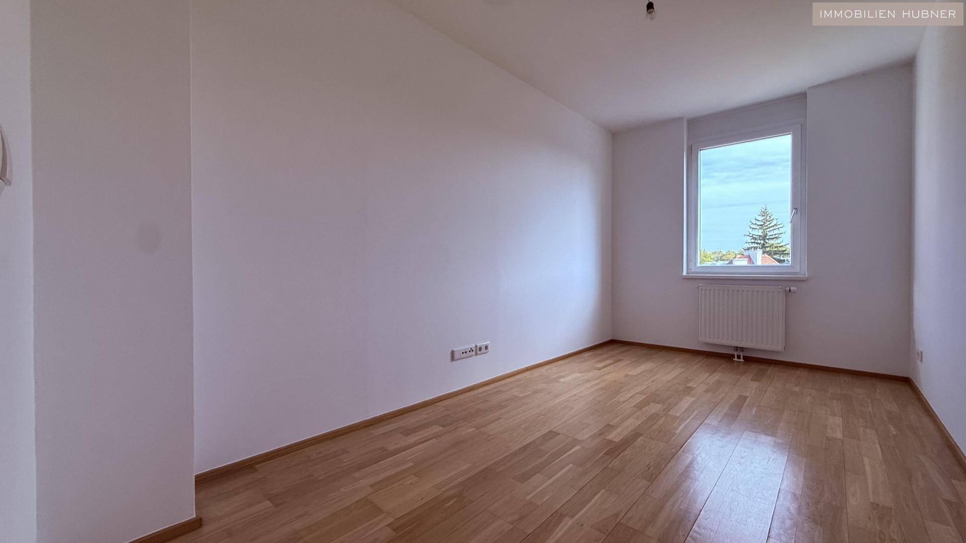 Ruhiges Schlafzimmer mit Holzboden und einem Fenster, das viel Tageslicht hereinlässt.