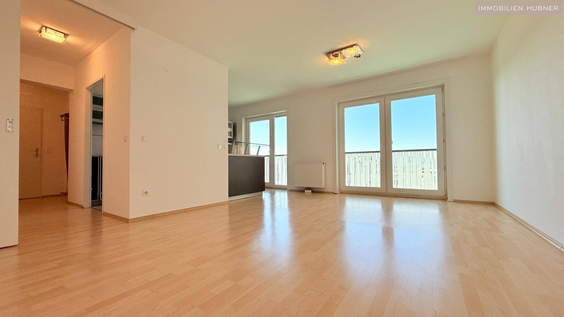 Helles Wohnzimmer mit hellem Parkettboden und Zugang zu einem Balkon, bereit zur individuellen Gestaltung.
