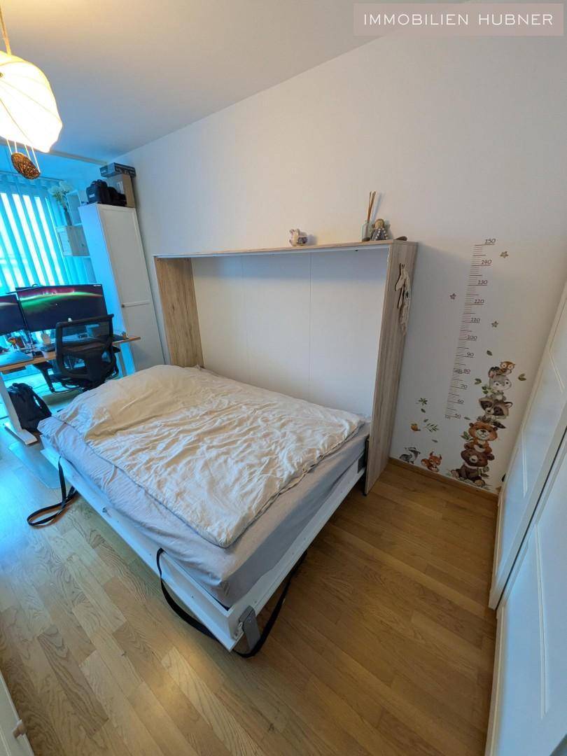Schlafzimmer mit einem praktischen Wandbett und Holzfußboden, das tagsüber Platz spart.