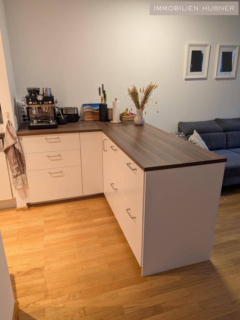 Funktionale Küche mit weißen Schränken und Holz-Arbeitsplatte, die sich nahtlos in den Wohnraum einfügt.