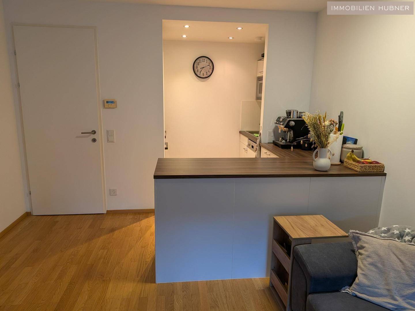 Semi-offene Küche mit Theke und integrierten Geräten, die zum Wohnbereich hin offen ist.
