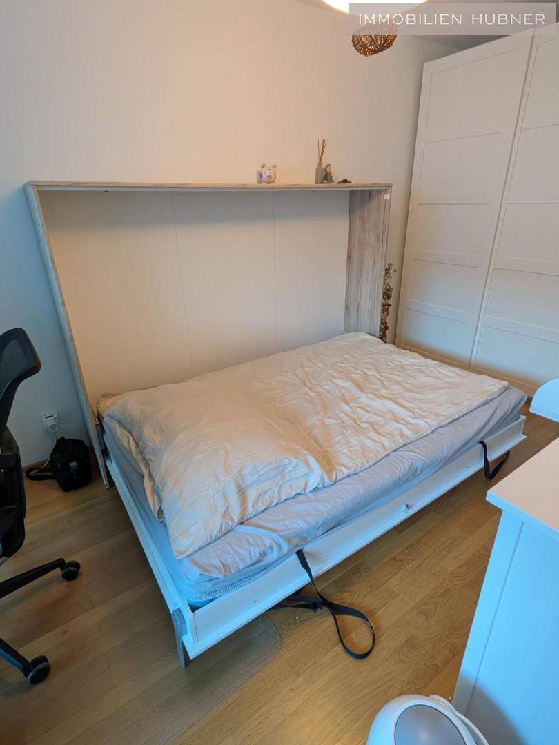 Ausgeklapptes Wandbett in einem hellen Raum mit Holzfußboden, bereit für eine erholsame Nacht.