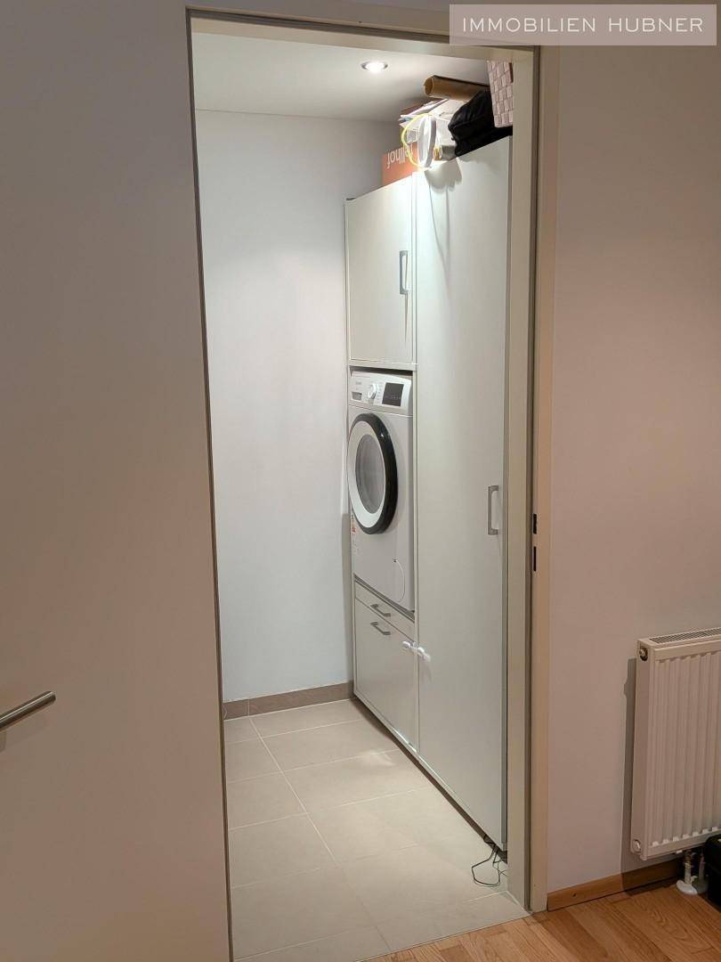 Praktischer Hauswirtschaftsraum mit Waschmaschine und Trockner, eingebaut in weiße Schränke.
