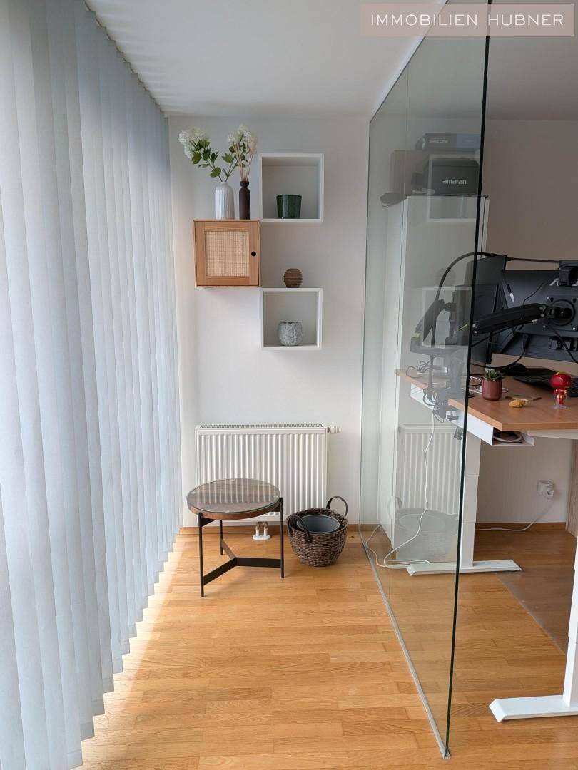Detailansicht des Arbeitsbereichs mit dekorativen Regalen und einem Heizkörper unter dem Fenster.