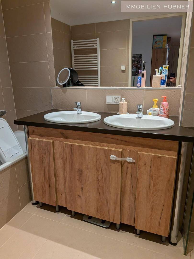Modernes Badezimmer mit Doppelwaschbecken, großem Spiegel und beheiztem Handtuchhalter.