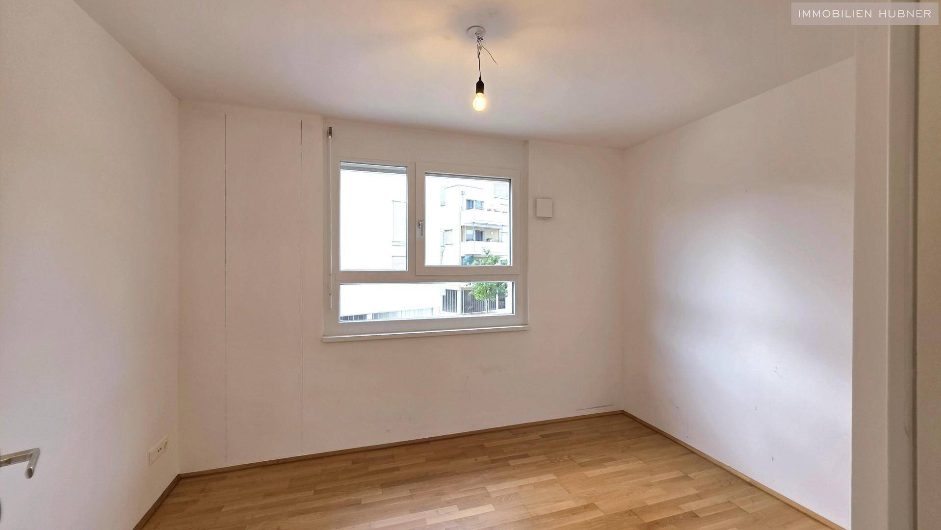 Weiteres Schlafzimmer mit Parkettboden und Fenster, bietet viel Tageslicht.
